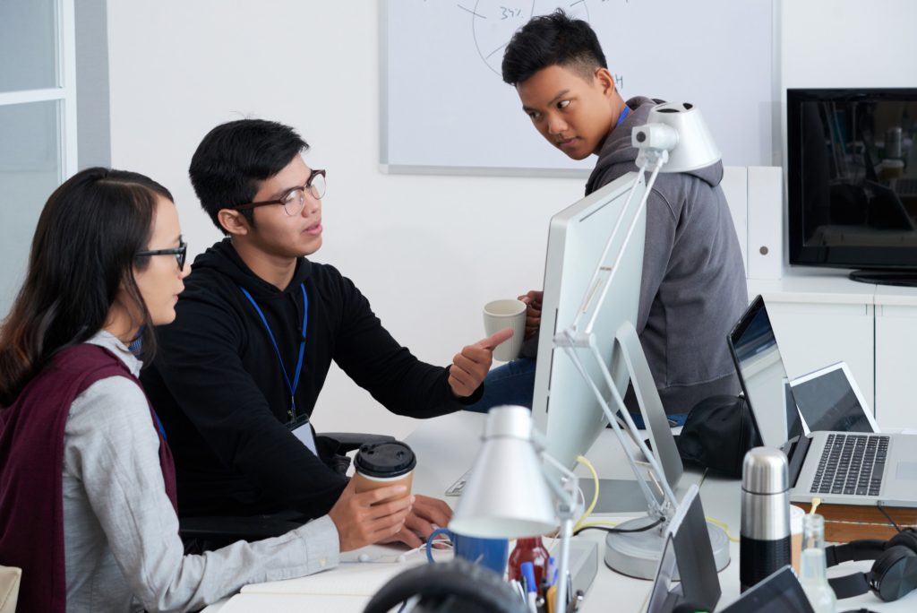 Alt Text: Tech workers discussing AI automation strategy at office computers